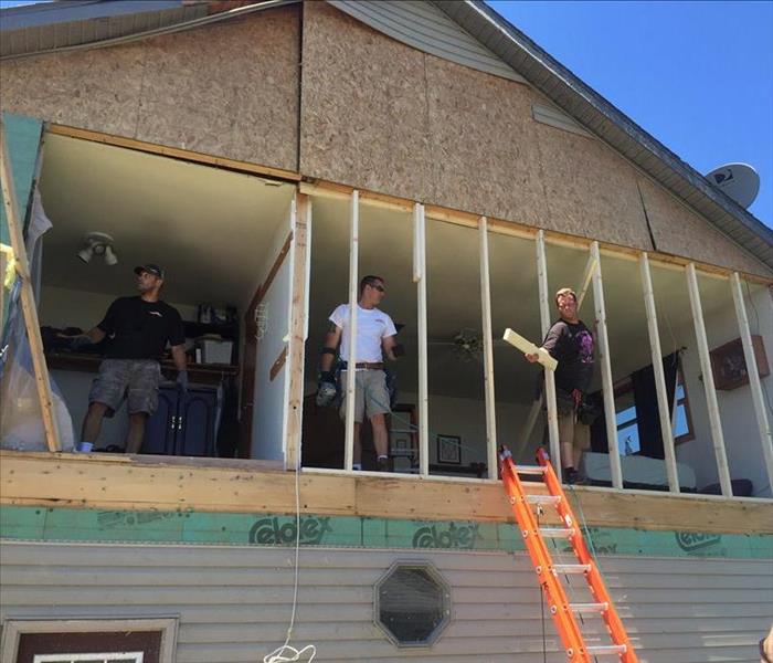 3 team members working on the exterior of a home after storm damage.