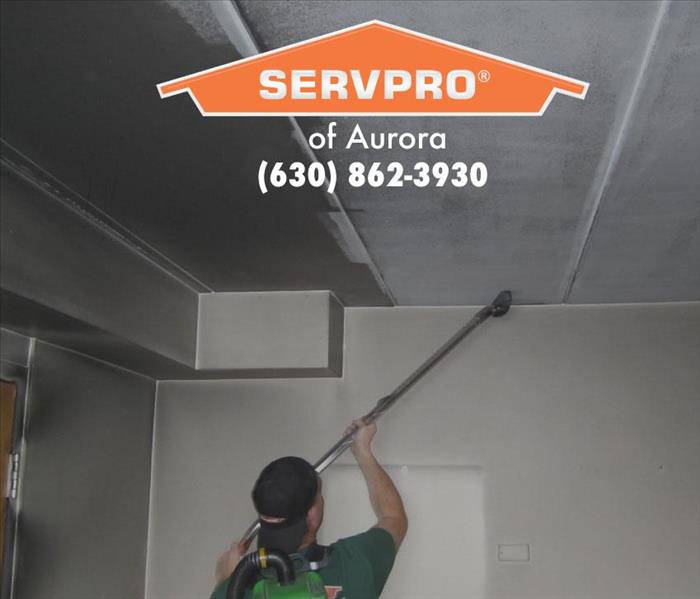 Team member cleaning ceiling and wall.