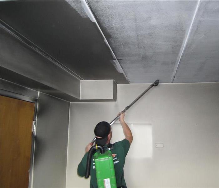Team member cleaning wall and ceiling.